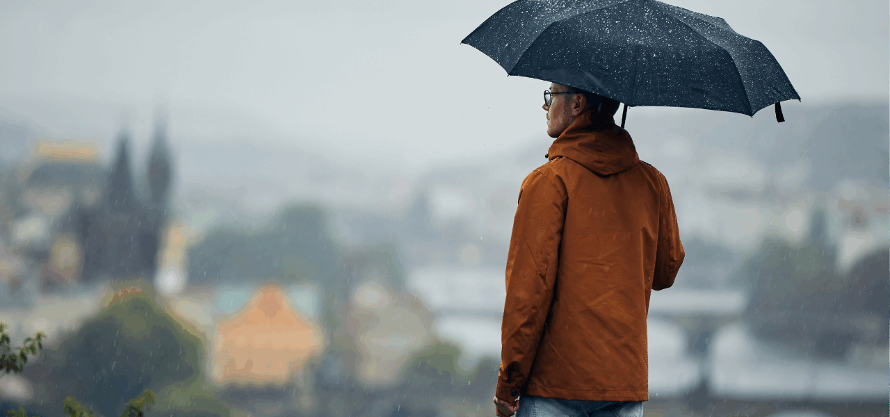 persona con paraguas mirando hacia el horizonte